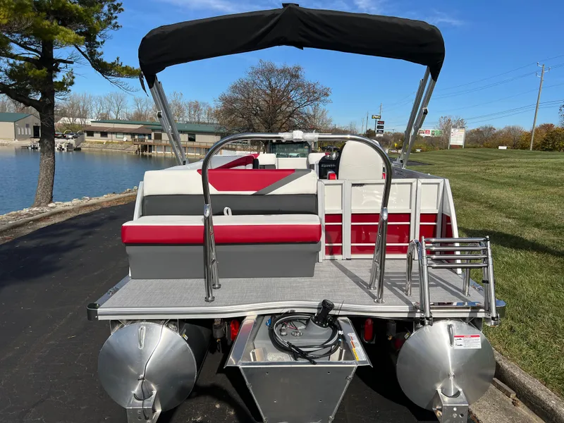 Slide: The Image of 2025 South Bay S 220 CR2 pontoon boat with red and gray seating, docked by a lake. - 5