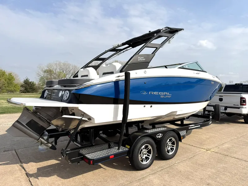 Slide: The Image of 2025 Regal LS4 Surf boat on trailer, blue and white design, parked outdoors. - 10