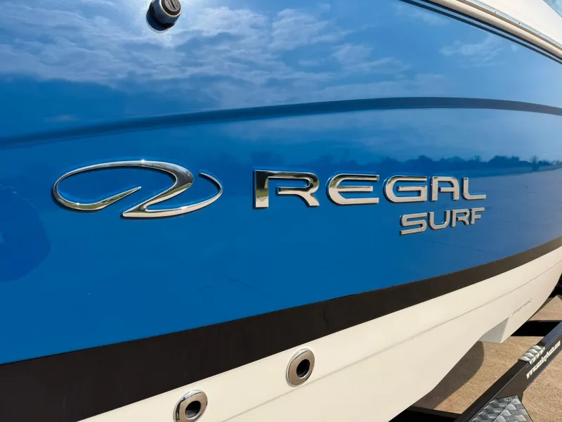 Slide: The Image of 2025 Regal LS4 Surf boat with blue and white exterior detailing. - 14