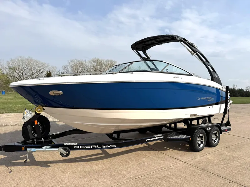 Slide: The Image of 2025 Regal LS4 Surf boat on trailer, blue and white design, parked outdoors. - 3