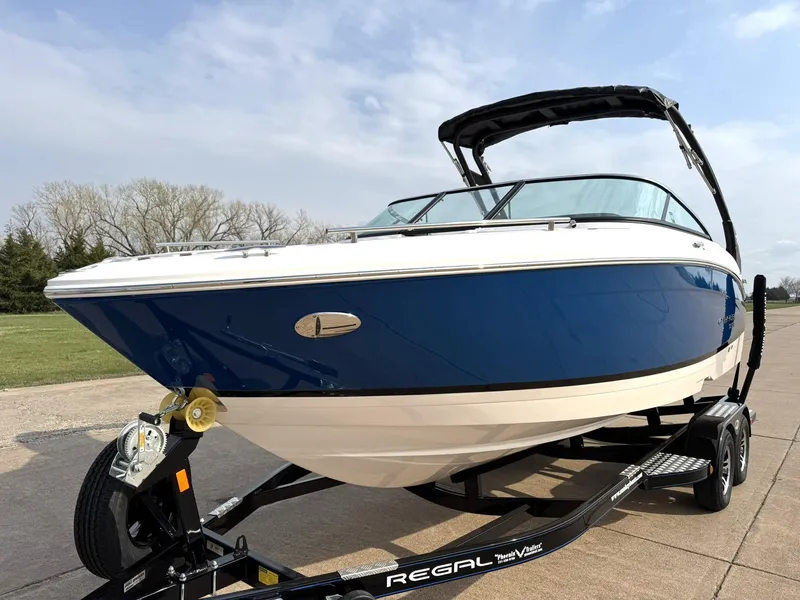 Slide: The Image of 2025 Regal LS4 Surf boat on trailer, blue and white design, parked outdoors. - 4