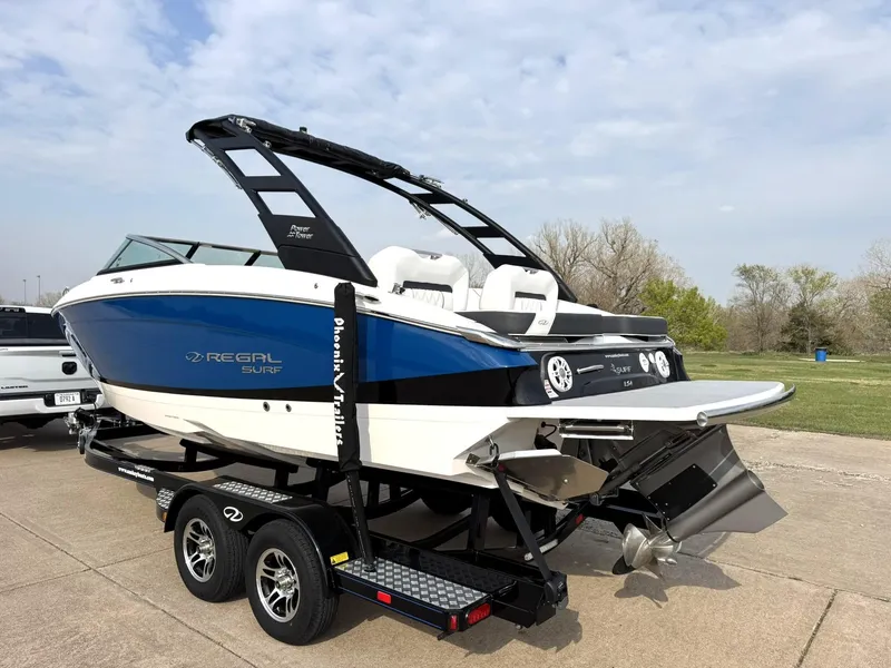 Slide: The Image of 2025 Regal LS4 Surf boat on trailer, blue and white design, parked outdoors. - 5