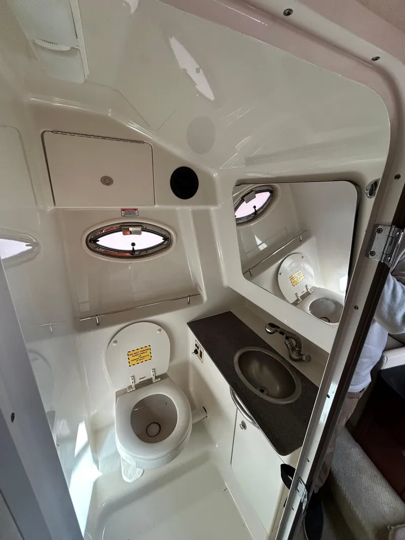 Slide: The Image of 2006 Sea Ray 290 Sundancer bathroom with sink, toilet, and porthole window. - 8