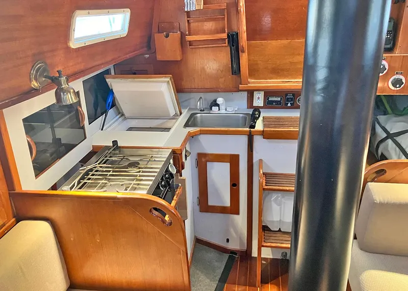 Slide: The Image of 1983 Freedom Cat Ketch yacht interior with compact kitchen and wooden cabinetry. - 9