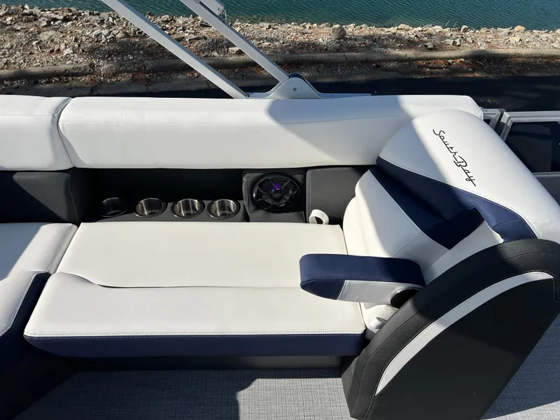 Slide: The Image of 2025 South Bay S 220CR2 boat interior with white and navy seating, cup holders, and speaker. - 20