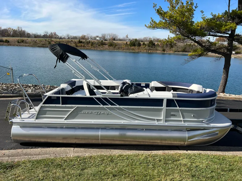 Slide: The Image of 2025 South Bay S 220CR2 pontoon boat by a serene lake. - 4