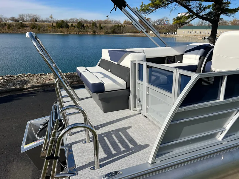Slide: The Image of 2025 South Bay S 220CR2 pontoon boat with seating, docked by a serene lake. - 6