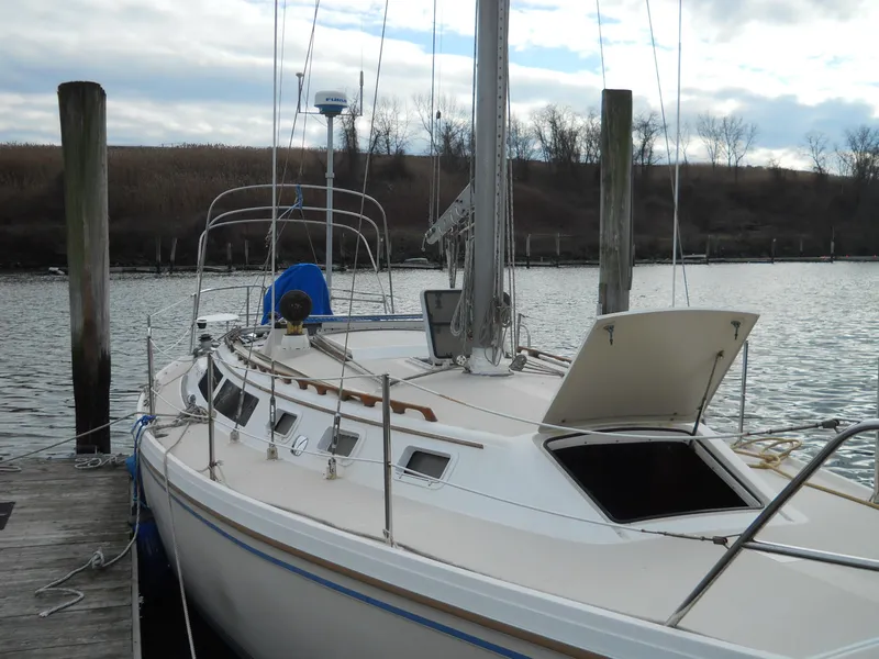 Slide: The Image of 1987 Catalina C-34 sailboat docked at a marina, with open hatch and calm water. - 3