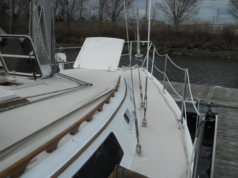 Slide: The Image of 1987 Catalina C-34 sailboat deck with open hatch, docked by a riverbank. - 4