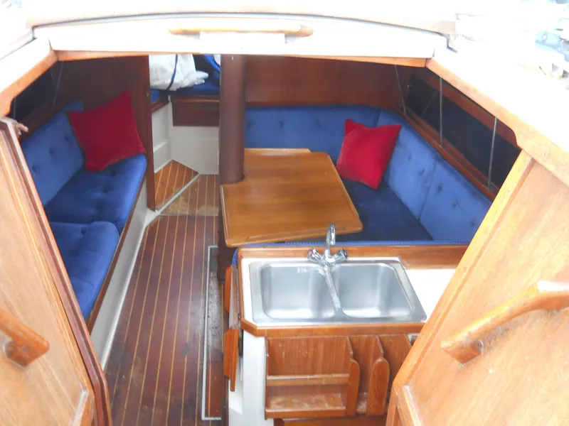 Slide: The Image of Interior of 1987 Catalina C-34 sailboat with blue seating, wooden table, and kitchen sink. - 6