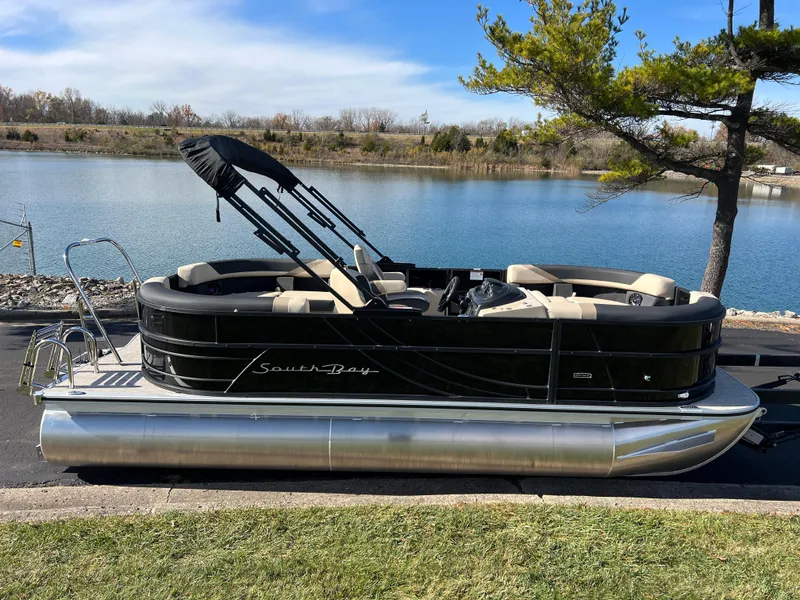 Slide: The Image of 2025 South Bay 220RS pontoon boat by a serene lake. - 0