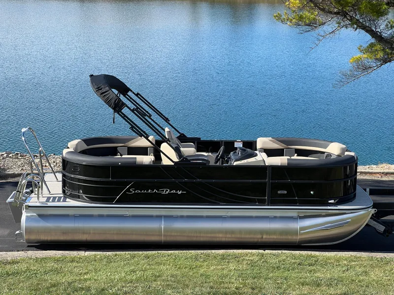 Slide: The Image of 2025 South Bay 220RS pontoon boat by a serene lake. - 1