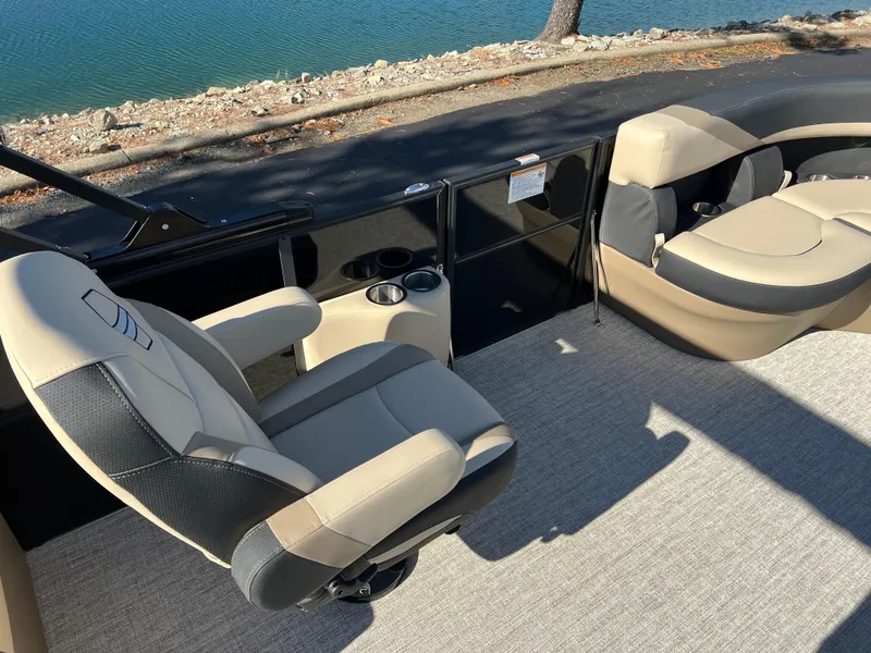 Slide: The Image of 2025 South Bay 220RS boat interior with beige and black seating by the water. - 17