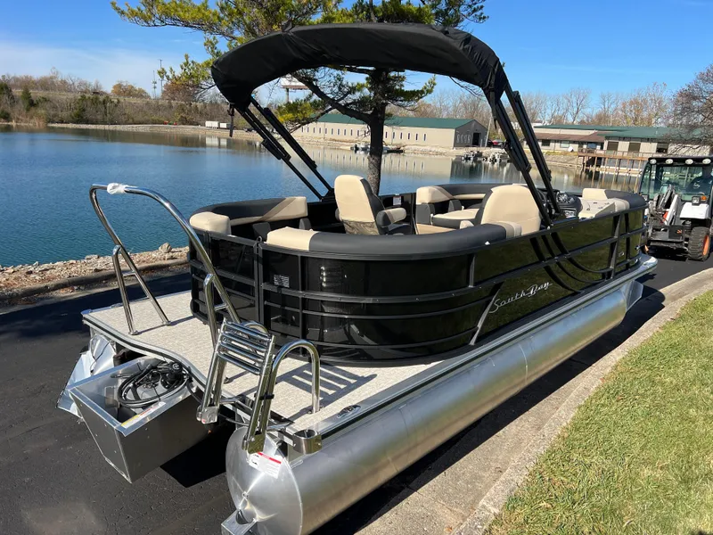 Slide: The Image of 2025 South Bay 220RS pontoon boat by a lake, featuring sleek black design and spacious seating. - 4