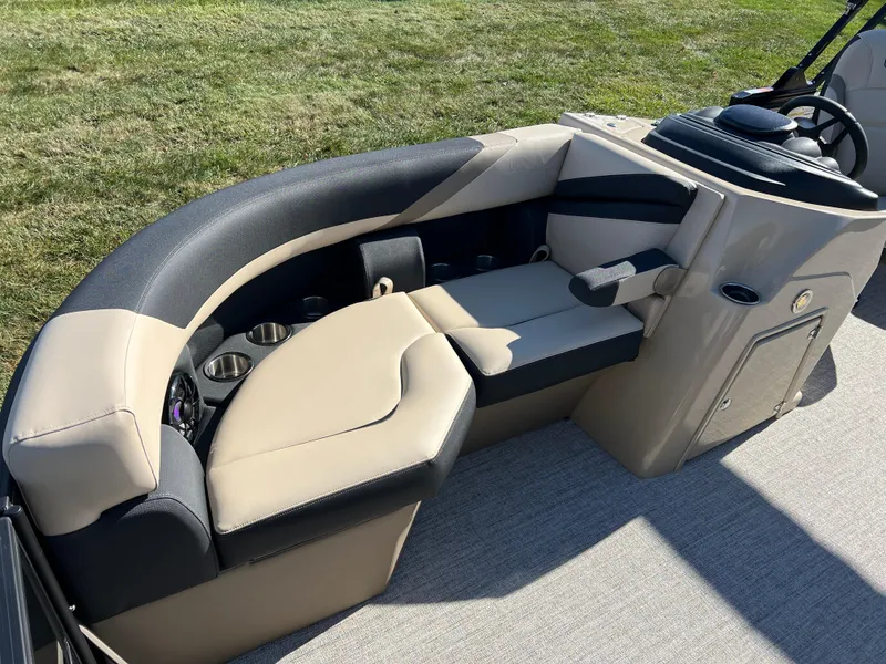 Slide: The Image of 2025 South Bay 220RS boat interior with beige and black seating, cup holders, and steering console. - 8
