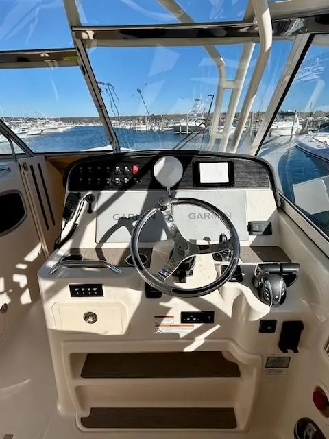 Slide: The Image of 2022 Grady-White Freedom 335 boat helm with steering wheel and navigation controls. - 12