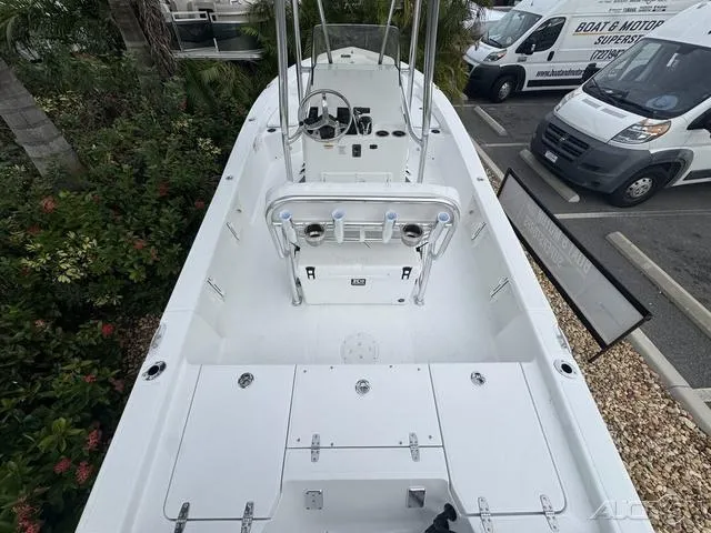 Slide: The Image of 2025 BlackJack 224 boat interior, white deck, steering console, parked near greenery and vehicles. - 12