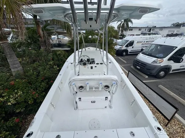 Slide: The Image of 2025 BlackJack 224 boat with center console, parked near palm trees and vehicles. - 13