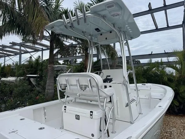 Slide: The Image of 2025 BlackJack 224 boat with T-top and seating, surrounded by tropical plants. - 6