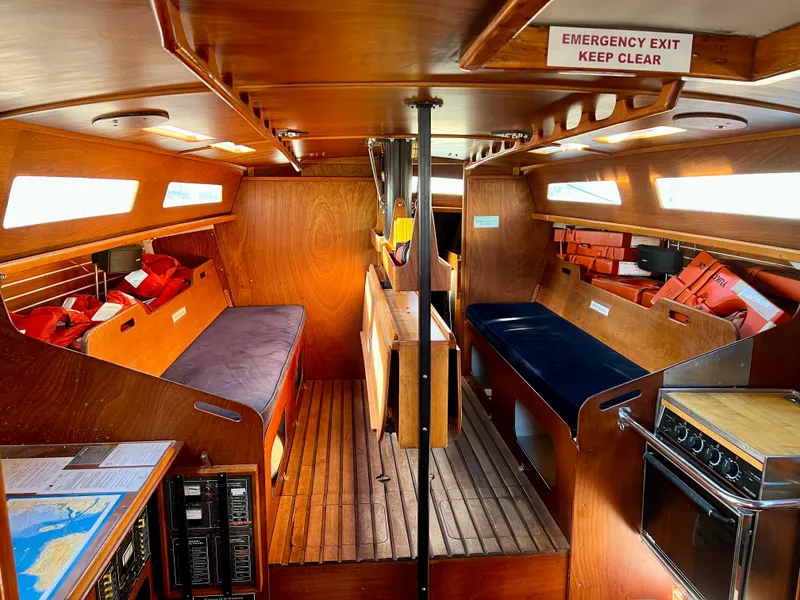 Slide: The Image of Interior of 1985 Santa Cruz 50 sailboat with wooden furnishings and emergency exit sign. - 15