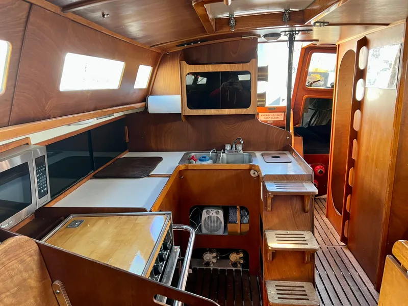Slide: The Image of Interior of a 1985 Santa Cruz 50 sailboat, featuring a wooden kitchen and modern appliances. - 16