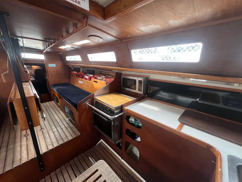 Slide: The Image of Interior of a 1985 Santa Cruz 50 sailboat with wooden furnishings and kitchen area. - 25
