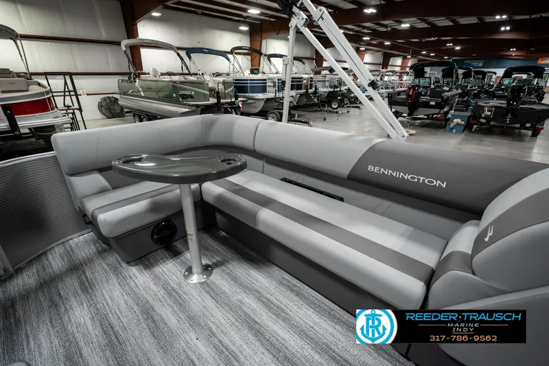 Slide: The Image of 2025 Bennington 22 SLSE pontoon boat interior with gray seating and table in showroom. - 22