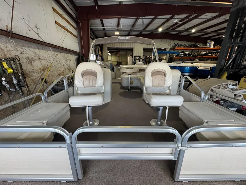 Slide: The Image of 2006 Godfrey Sweetwater 2186 DF pontoon boat in storage, featuring spacious seating and fishing gear. - 2