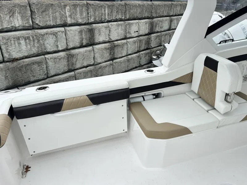 Slide: The Image of Edgewater 262CX 2022 boat interior with beige and white seating, near stone wall. - 12
