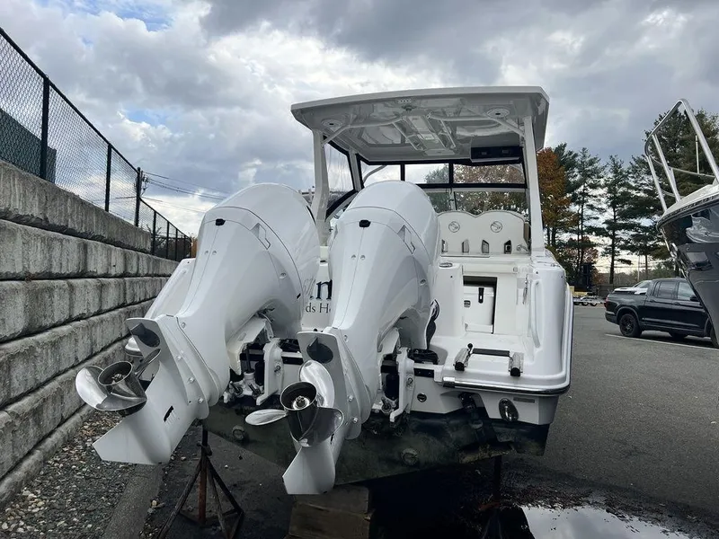 Slide: The Image of 2022 Edgewater 262CX boat with dual outboard motors, parked outdoors under cloudy skies. - 3