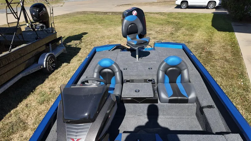 Slide: The Image of 2023 Vexus AVX2080 boat with blue and black seating, parked on grass. - 12