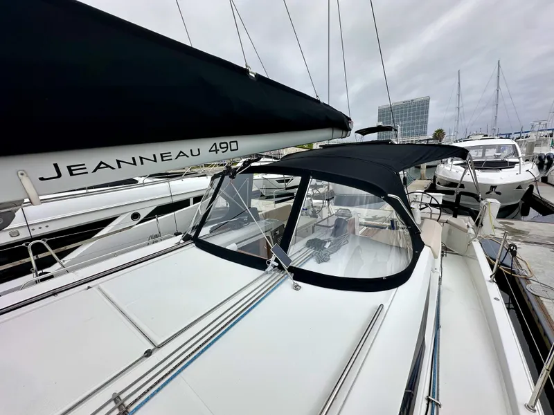Slide: The Image of 2020 Jeanneau Sun Odyssey 490 sailboat docked at marina, featuring sleek design and black canopy. - 44