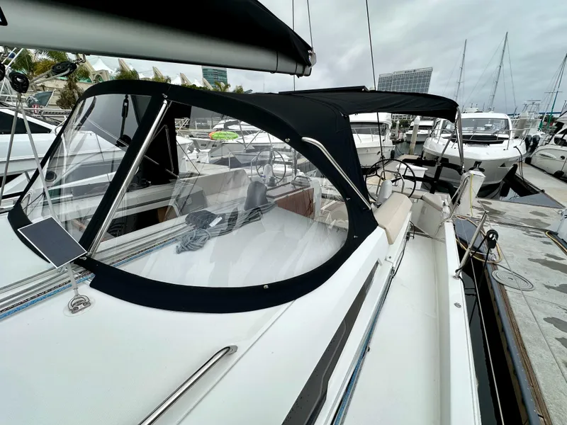 Slide: The Image of 2020 Jeanneau Sun Odyssey 490 sailboat docked at marina, featuring sleek design and covered cockpit. - 45