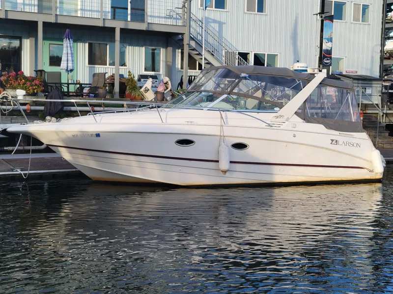 The Image of 1997 Larson 290 CABRIO boat docked at marina, white exterior, calm water reflection. - 0