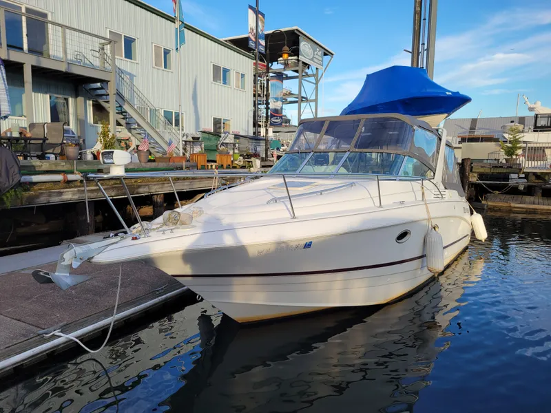 Slide: The Image of 1997 Larson 290 Cabrio boat docked at marina with blue canopy. - 10