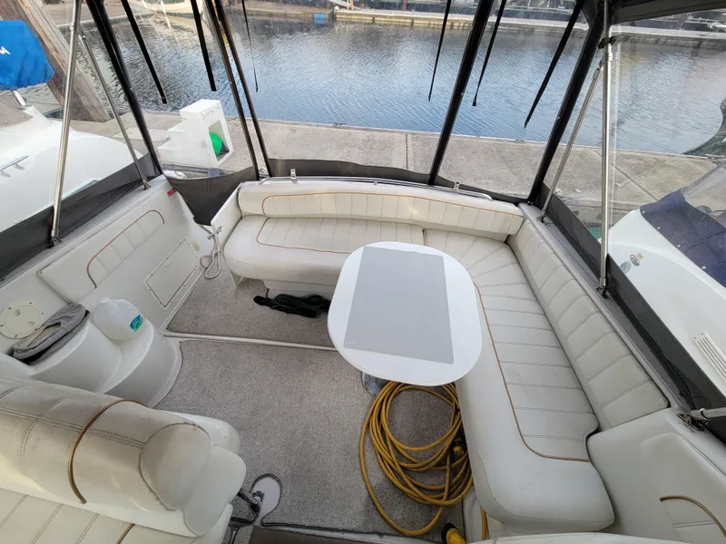 Slide: The Image of 1997 Larson 290 Cabrio boat interior with white seating and table, docked by the water. - 16