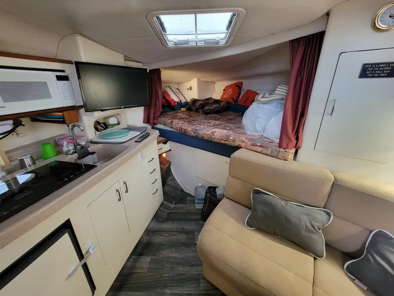 Slide: The Image of 1997 Larson 290 Cabrio cabin interior with kitchenette, seating, and sleeping area. - 30