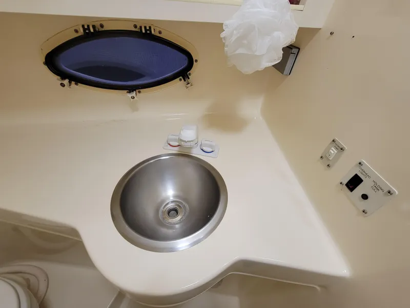 Slide: The Image of 1997 Larson 290 CABRIO boat bathroom sink with porthole and toiletries. - 34