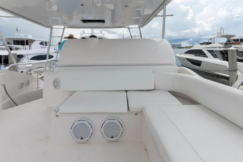 Slide: The Image of 2004 Bertram 630 yacht interior with white seating and speakers, docked at marina. - 15