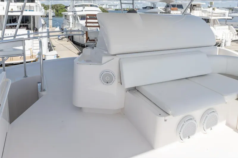 Slide: The Image of 2004 Bertram 630 yacht deck with white seating and speakers, docked at marina. - 20