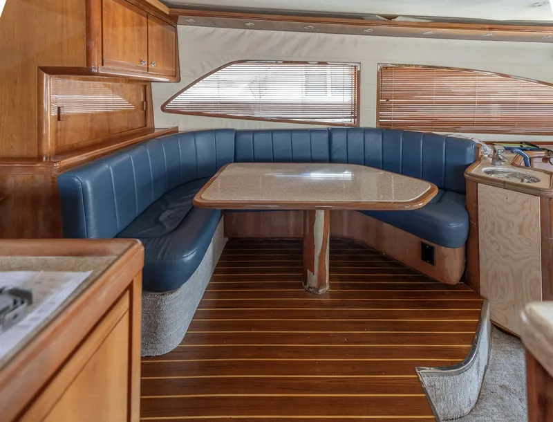 Slide: The Image of 2004 Bertram 630 yacht interior with blue seating and wooden table. - 5