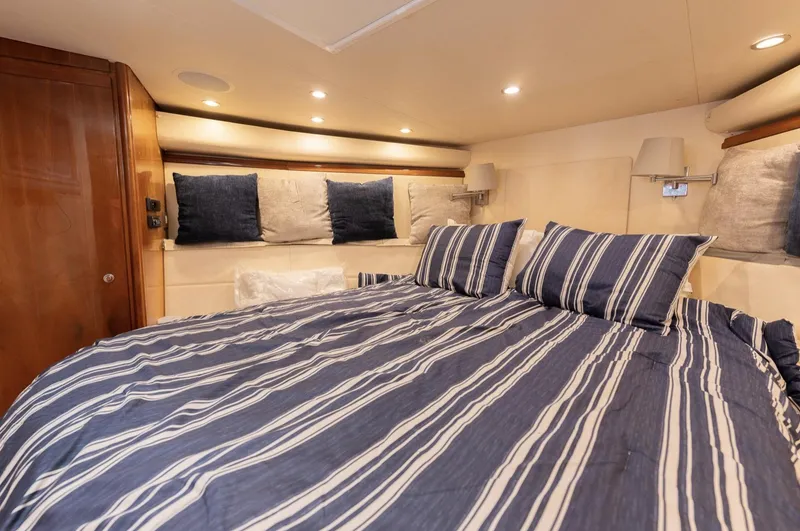 Slide: The Image of Luxurious bedroom interior of 2004 Bertram 630 yacht with striped bedding. - 7