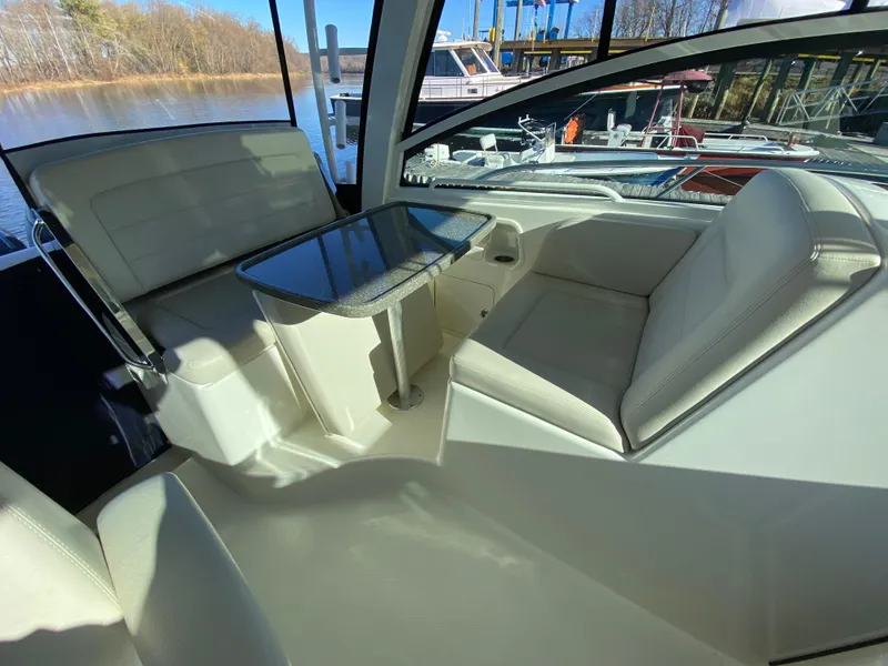 Slide: The Image of 2020 Boston Whaler 345 Conquest interior with white seating and table, docked by the water. - 10