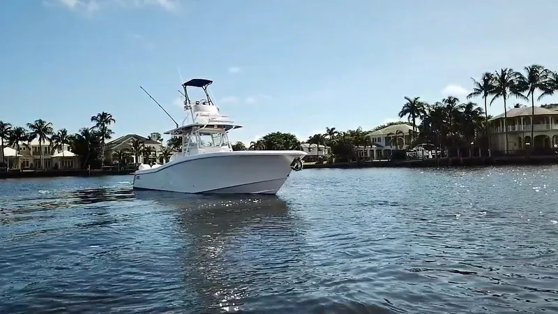 Slide: The Image of 2020 Invincible 39 Open Fisherman boat on calm water, surrounded by palm trees and houses. - 2