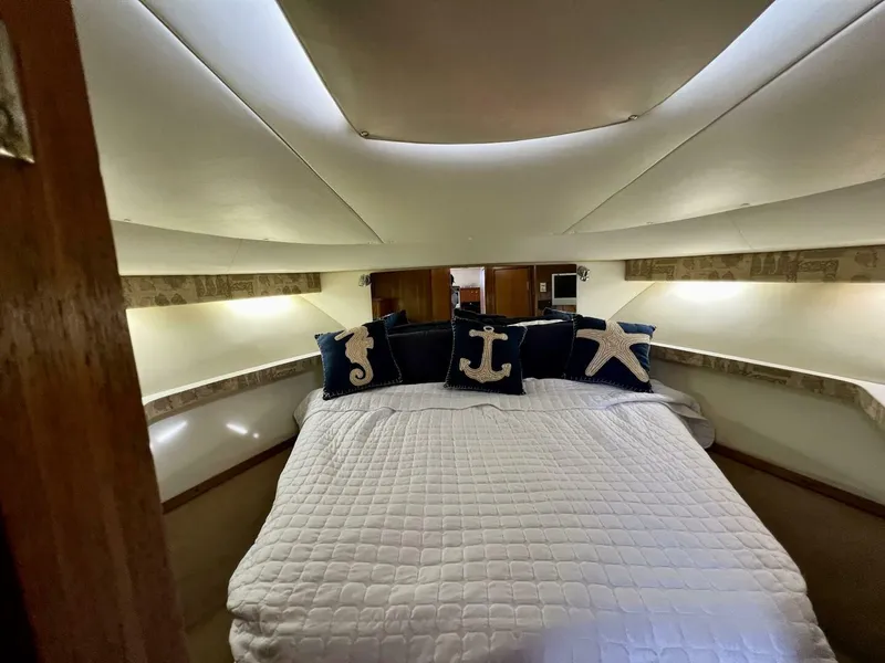 Slide: The Image of Luxurious 1997 Tiara Yachts 41 cabin with nautical-themed pillows and cozy bedding. - 11