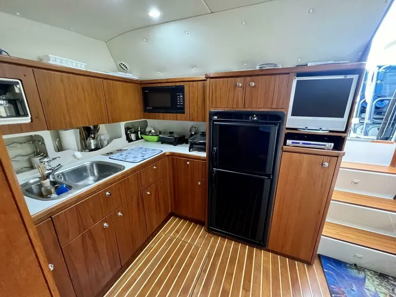 Slide: The Image of 1997 Tiara Yachts 41 interior kitchen with wood cabinetry, sink, microwave, fridge, and TV. - 9