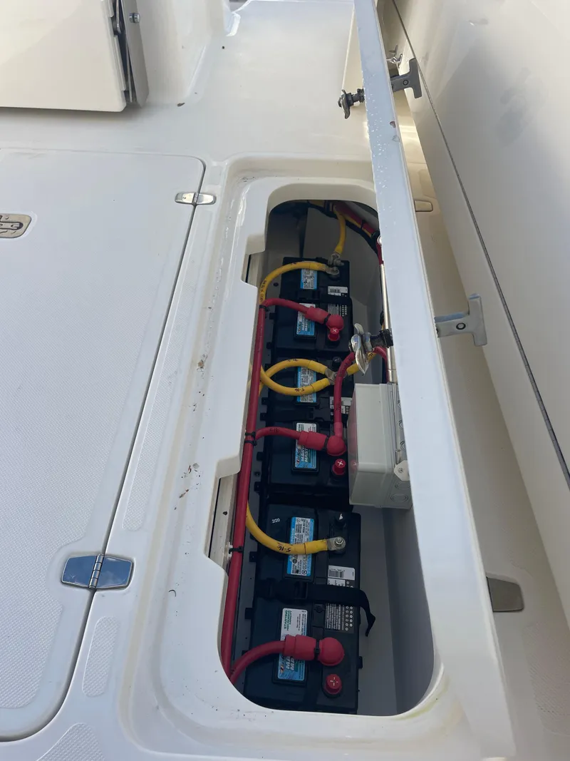 Slide: The Image of 2020 Pursuit 385 Offshore boat battery compartment with multiple batteries and wiring. - 14