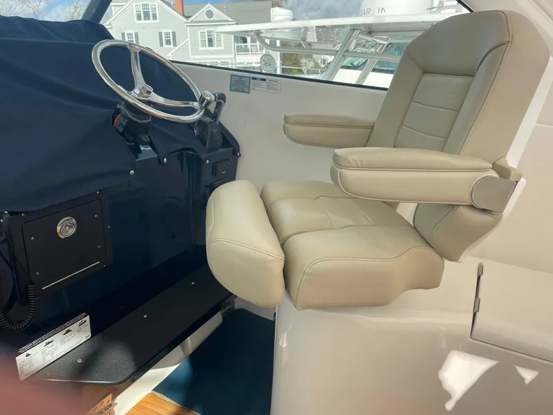 Slide: The Image of 2020 Pursuit 385 Offshore helm with beige captain's chair and steering wheel. - 20