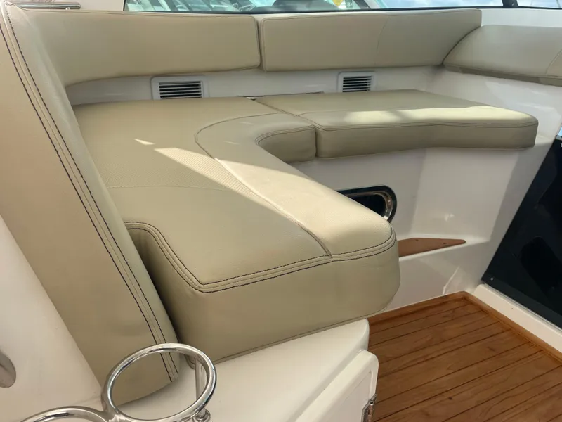 Slide: The Image of 2020 Pursuit 385 Offshore boat interior with beige seating and wooden flooring. - 23