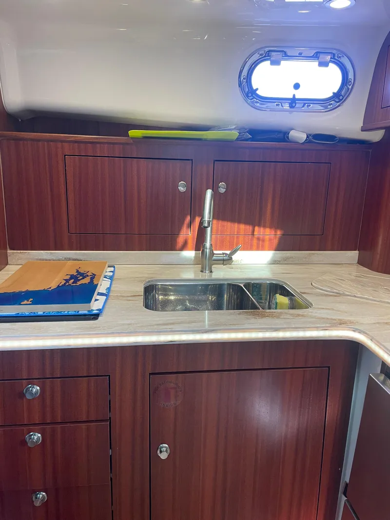 Slide: The Image of 2020 Pursuit 385 Offshore yacht kitchen with wood cabinets and stainless steel sink. - 27